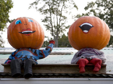 Painted Pumpkin Figures Wave from the Roof of a Roadside Stand