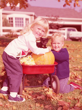Boy and Girl With Kitten, Flowers and Pumpkin in Wagon in Backyard